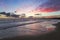 Enchanting sunset. Storm sea with high waves. Unbelievable blue, pink, orange colors of the sky are reflected on the wet sand.