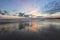 Enchanting sunset. Storm sea with high waves. Unbelievable blue, pink, orange colors of the sky are reflected on the wet sand.