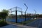 An enclosed blue court for padel with construction created by mesh and the glass back walls.