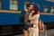 Encounter after a travel of a happy couple hugging in the street in a train station. Beautiful evening warm sunlight