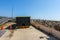 The end of a empty black dumpster is seen at a construction site by a boardwalk at the beach