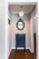 End of the hall hallway decor of accent piece of furniture cabinet with an ornate black mirror hanging above it and an accent pend
