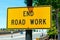 End Road Work traffic sign. Background wide urban street with a few cars