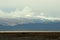 Endless autumn steppe with stone boulders at the foot of a mountain range with snow-capped peaks