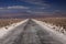 Endless dirt road with blurred horizon through salt flat