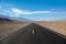 Endless and lonely blacktop road going into the mountain range entering Death Valley National Park