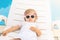 Endless summer! Cute baby relaxing at sunbed near pool, resort.