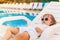 Endless summer Cute baby relaxing at sunbed near pool, resort.