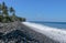 An endless virgin pebble beach with palm trees and tropical vegetation on Bali Island in Indonesia. The waves wash the stony coast