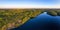 Endless wild forest and clear blue lake aerial panoramic landscape at sunset
