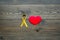 Endometriosis. Gynecological diseases concept. Symbolic yellow ribbon near heart sign on dark wooden background top view