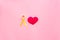 Endometriosis. Gynecological diseases concept. Symbolic yellow ribbon near heart sign on pink background top view copy