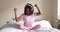 Energetic black woman dancing in bed, listening to music