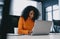 Energetic businesswoman in a lively orange sweater engaged in a video call