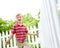 Energetic and excited in his backyard. A cute young boy running a stick along a white picket fence in his backyard.