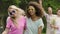 Energetic female couple dancing, smiling for camera, enjoying picnic in park