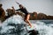 Energetic girl active riding wave on surf style wakeboard and lifting up lot of splashes