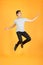 Energetic happy young Asian man in casual clothes jumping, studio shot isolated in orange background