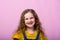 Energetic joyful adorable little girl laughing at joke on pink background