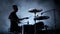 Energetic musician plays good music on drums. Black smoky background . Side view. Silhouette