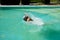 energetic senior man swimming in summer pool on summertime vacation