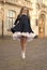 Energetic small kid in elegant uniform dress jump in school yard outdoors, schooling