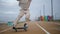 Energetic teen riding skateboard on road sea coast. Skater feet making trick