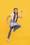 Energetic teenage girl running while listening to music in headphones yellow background, fun