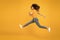 Energetic woman running or jumping. Skinny jeans suits her. Sexy girl yellow background. Sensual girl in casual style