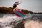 Energetic young woman skillfully jumping over splashing river wave on surf style wakeboard.