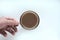 Energy boost concept. Hand holding a glass mug of coffee, white background, top view.