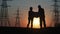 Energy efficiency concept, a team of engineers in protective helmets a man and a woman discussing high-voltage poles