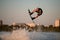 energy muscular male wakeboarder makes extreme stunts jumping on wakeboard over splashing wave