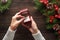 Engagement ring in female hands among Christmas decorations on wood background