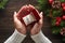 Engagement ring in female hands among Christmas decorations on wood background