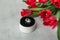 Engagement ring with giant diamond in a round white box on a sharpen grey background and with a bouquet of red tulips
