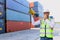 Engineer boss with safety vest and helmet holding megaphone speaker for communicating with worker staff at logistic shipping cargo