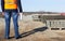 An engineer with a folder in the signal vest checks the quality of the curb for the construction of a new road, inspector