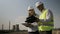 Engineer and foreman analyzing industrial field plans and completing on clipboard work progress report near oil gas refinery -