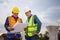 Engineer and foreman worker checking project at building site, Engineer and builders in hardhats discussing blueprint on