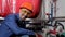 An engineer in glasses works in the boiler room, checks the maintenance of the heating system equipment