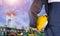 Engineer hand holding yellow safety helmet with blurred background of crude oil tanker at shipyard