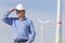 Engineer with hard hat in front of a windfarm looking for a bright future for green energy