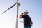 Engineer in hard hat holds a plan project for the construction of wind turbines in the field against the background of