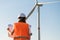 Engineer in hard hat and protective vest holds a paper plan project for the construction of wind turbines in the field