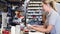 Engineer helping female apprentice in factory to measure component using micrometer