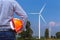 Engineer holding yellow safety helmet front wind turbines generating electricity power station