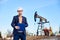 Engineer making notes standing in oilfield, behind him - oil pump jack