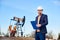 Engineer making notes standing in oilfield, behind him - oil pump jack