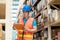 Engineer man wearing safety helmet and vest holding clipboard and take note on the paper in the automotive part warehouse.